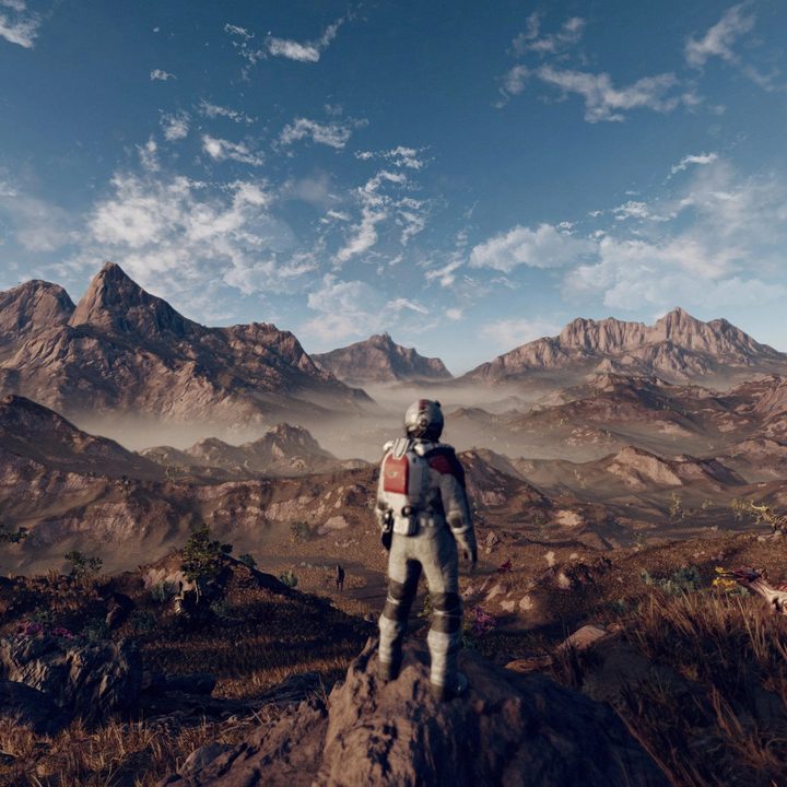 A space explorer stands in front of a mountain range in Starfield.